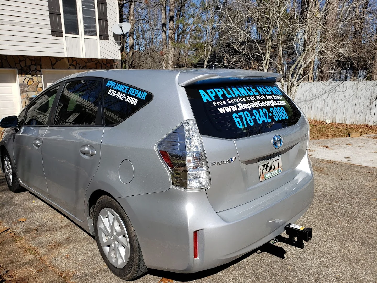 Appliance repair vinyl decals on rear window of a silver car
